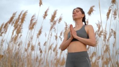 Kamış üzerinde namaste yoga mudra yapan güzel bir kadın. Plajda armoni eğitimi alan sağlıklı bir bayan. Minnettarlık, aşk, zen, sağlık konsepti.