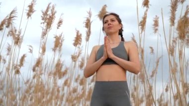 Kamış üzerinde namaste yoga mudra yapan güzel bir kadın. Plajda armoni eğitimi alan sağlıklı bir bayan. Minnettarlık, aşk, zen, sağlık konsepti.