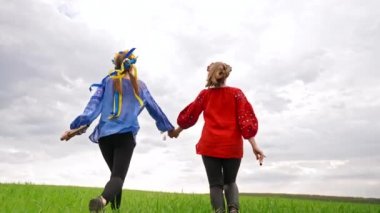 Koşan mutlu kadınlar, ellerinde flüt, ellerinde Ukraynalı sopilka. Yeşil alan. Nakış işlemeli genç arkadaşlarının portresi - ulusal bluz. Ukrayna, arkadaşlık, etnik müzik konsepti.