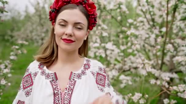 Çiçek bahçesinde geleneksel şenlikli nakış işlemeli muhteşem bir kadın. Ukrayna vyshyvanka, ulusal kostüm. Gülümseyen güzel kız, neşeli bayan. Doğa arkaplanı. — Stok video