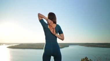 Gomukhasana 'da pratik yapan bir kadın. İnek başı pozu, yüksek dağda su üstünde yoga. Doğada esneklik egzersizi. Güçlü kadın boyun ve sırt güçlendiriyor.
