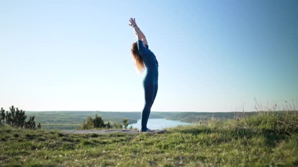 Молодая женщина в синей спортивной одежде практикует йогу на высоких горах. Красивая сцена. Комплекс асанас Сурья Намаскар, баланс. Фитнес, спорт, концепция здорового образа жизни. — стоковое видео