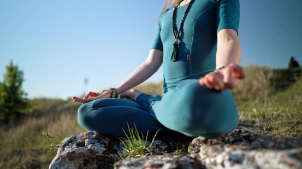 Young woman in blue overalls relax, doing yoga outdoor on nature, closeup of hands, gyan mudra and lotus pose. Dolly shot. Healthy lifestyle, breathe deeply, bright mind concept. — Stock Video