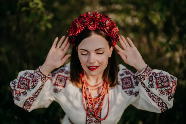 Vonzó ukrán nő hagyományos hímzéses vyshyvanka ruhában, ősi korallgyöngyökkel és vörös virágkoszorúval. Ukrajna, szabadság, kultúra, nemzeti jelmez, győzelem a háborúban. — Stock Fotó