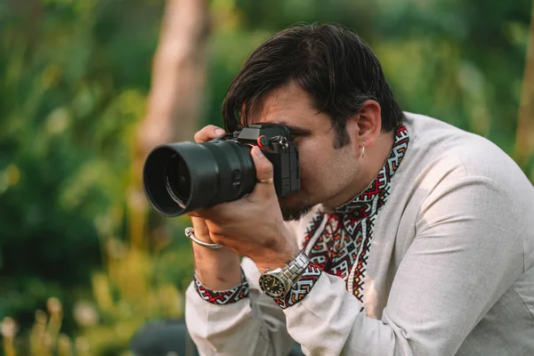 Muž fotograf fotografování na profesionální digitální fotoaparát venku. Kameraman pracující s vybavením DSLR. — Stock fotografie