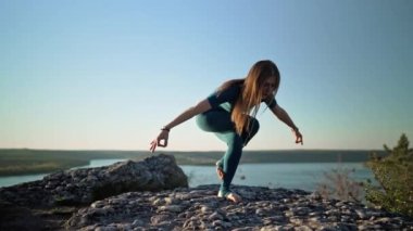 Garudasana 'da pratik yapan muhteşem bir kadın. Kartal pozu, suyun üstündeki yüksek dağda yoga. Özgür ve vahşi. Doğada esneklik egzersizi. Güçlü kadın boyun ve sırt güçlendiriyor, denge