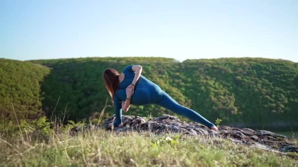 Woman practicing in Gomukhasana - cow head pose, yoga on high mountain. Flexibility workout at nature background. Strong lady strengthening neck and back — Stock Video