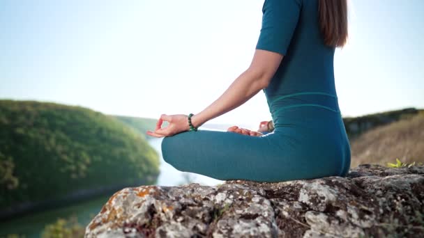 Невпізнавана мирна жінка йоги, що сидить у лотосі, роздумуючи, вільно почуваючись перед дикою природою. Тільки руки. Уважний тренер з фітнесу має момент дзен. Повсякденна практика йоги, концепція дихання — стокове відео