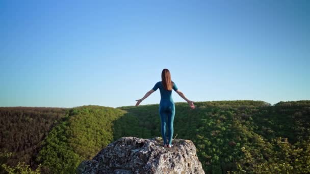 Жінка-йоги досягає вершини скелі на високій горі і починає практику йоги з глибоким диханням. Дика природа, вільна людина. Свобода, практика, цілі — стокове відео