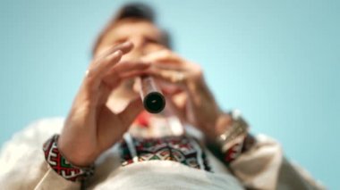 Ahşap flüt çalan genç adamın elleri. Ukraynalı sopilka açık havada. Halk müziği konsepti. Müzik aleti. Geleneksel nakışlı gömlekli müzisyen - Vyshyvanka.