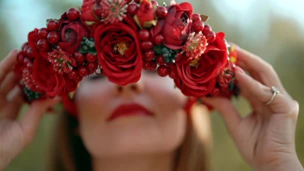 Украинка надевает головной венок из красных цветов и вибурнума. Она восхищается ее традиционным украшением головы. — стоковое видео