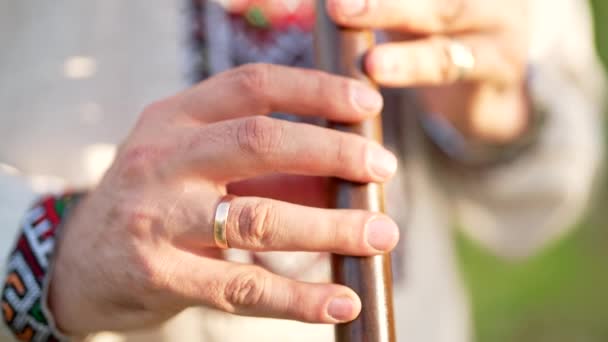 Händer av ung man spelar på träblåsare trä flöjt - ukrainska sopilka utomhus. Folkmusikkoncept. Musikinstrument. Musiker i traditionell broderad skjorta - Vyshyvanka. — Stockvideo