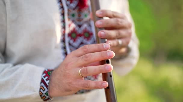 年轻男子的手在室外吹奏木管乐器长笛- -乌克兰女高音。民谣音乐概念。音乐乐器。传统绣花衬衫音乐家- Vyshyvanka. — 图库视频影像