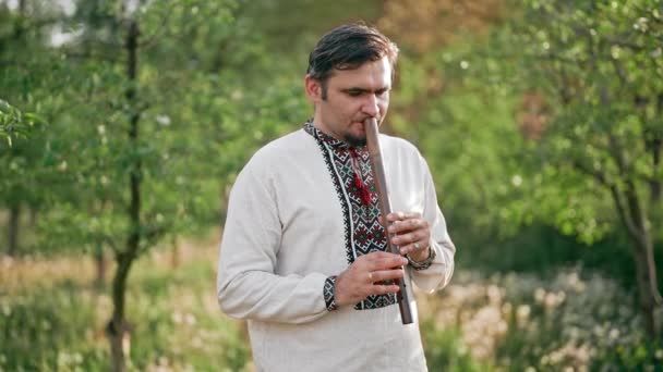 年轻人在室外吹奏木管乐器长笛- -乌克兰女高音.民谣音乐概念。音乐乐器。传统绣花衬衫音乐家- Vyshyvanka. — 图库视频影像