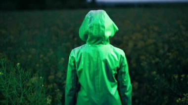 Tarlada yürüyen ürkütücü uzaylı. Düz yağmurluk giymiş insan kılığına girmiş yeşil dünya dışı varlıkların korkunç görüntüleri. UFO, fantezi, fütürist, kurgu konsepti. Çak bakalım.