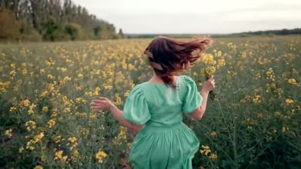 菜の花の牧草地 素晴らしい肯定的な映像の花の間で実行している若い女性 春の田舎の自然場所でロマンチックな無料の女性 高品質4K映像 — ストック動画