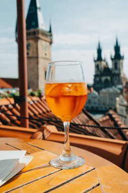 Prag şehir meydanının arka planında Aperol Spritzes kokteyli, kiliseyle birlikte, astronomik saat. Ünlü tarihi, gotik tarzda binalar. Avrupa başkentindeki güneşli şehir manzarası. Yüksek kalite fotoğraf