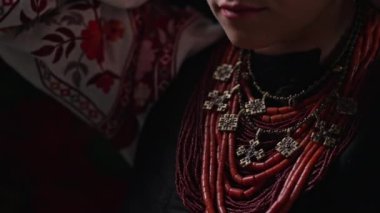 Ukrainian woman takes off authentic jewelry necklace. She is in national costume of Ukraine - vyshyvanka and ancient coral beads, Zgarda - archaic hutsul neck ornament of status religious purpose. 4k