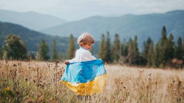 Sevgili küçük çocuk, Ukraynalı vatansever çocuk ulusal bayrağı açık alanda, Karpat dağının çayırında. Ukrayna, barış, bağımsızlık, özgürlük, savaşta kazanmak. Yüksek kalite 