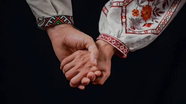 Young ukrainian couple in embroidered national shirts holding hands. Man and woman on black background. Lovers, family, trust, love and happiness concept. High quality