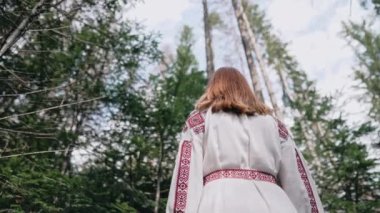 Ukraynalı kadının geçmişi Karpat Dağları 'ndaki köknar ormanında duruyor. Geleneksel nakış işlemeli vyshyvanka elbiseli kız. Ukrayna, özgürlük, etnik ulusal kostüm. Yüksek kalite 4k görüntü