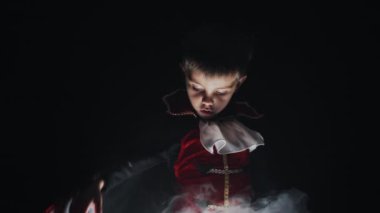 Vampir Dracula kostümlü komik küçük çocuk dumanlı siyah arka planda uçan manto. Cadılar Bayramı, şeker mi şaka mı, parti dekorasyonu konsepti. Yüksek kalite 4k görüntü