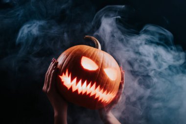 Buğulanmış balkabağı şeytanca gülüyor - oyulmuş gözleri ve dumanlı sırıtışı olan balkabağı fenerinin başı. Cadılar Bayramı 'nın sembolü, şeker mi şaka mı? Yüksek kalite fotoğraf