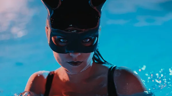 夜にプールでプールで泳ぐウサギのラテックスマスクのセクシーな女性 黒水着でパーティータイムを楽しむ魅力的な女の子 豊かなライフスタイル 豪華な生活 エンターテイメント 仮面舞踏会 危険な女だ 高品質 — ストック写真