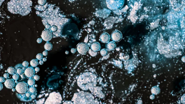 Abstract of frost bubbles bursts and dissolves in black paint. Blue sphere shapes. Detailed background, beautiful design, ice balloons texture. High quality photo