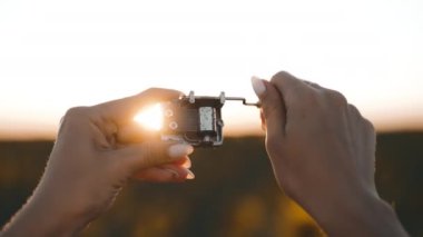 Eski müzik kutusu mekanizmasının dişli dişli kadın elleri. Retro küçük metalik carillon kolu çeviren bir kadın. Ayçiçeği tarlasında çalan müziği dinleyen bir kadın. Yüksek kalite 4k görüntü