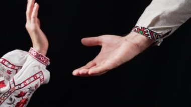 Young ukrainian couple in embroidered national shirts holding hands. Man and woman on black background. Lovers, family, trust, love and happiness concept. High quality 4k footage