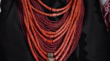 Ukrainian woman puts on authentic jewelry - coral beads. She is in national costume of Ukraine - vyshyvanka. Folk handmade necklace in traditional style. High quality 4k footage