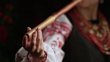 Tahta flüt çalan kadının elleri. Karanlık arka planda Ukrayna sopilkası. Halk müziği konsepti. Müzik aleti. Geleneksel nakışlı gömlekli müzisyen Vyshyvanka. Yüksek 4K görüntü