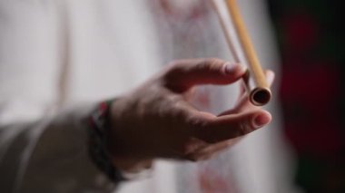 Tahta flüt çalan adamın elleri. Karanlık arka planda Ukrayna sopilkası. Halk müziği konsepti. Müzik aleti. Geleneksel nakışlı gömlekli müzisyen Vyshyvanka. Yüksek 4K görüntü