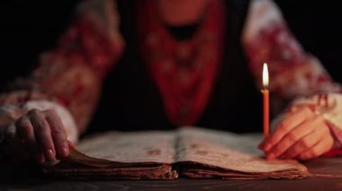 Ukraynalı kadın İncil 'i okuyor. Dikkatli bir şekilde mum ışığı altındaki kağıt sayfaya odaklanmış. Kyiv Rus tarihi. Mezmur, 19. yüzyıl, dualar ve ilahiler. Yüksek kalite 4k