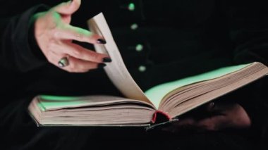 Kara Cadı Kadın 'ın elleri eski büyü kitabının sayfalarını çeviriyor. Sihirbaz büyüler, ritüeller, esrarengiz cadılar bayramı kostümü konsepti öğreniyor. Yüksek kalite 4k görüntü