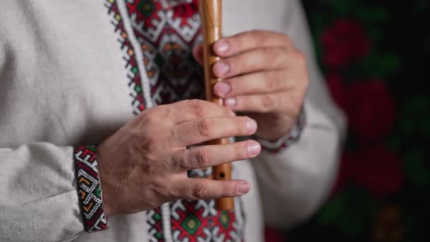 用木管乐器吹奏的人的手 黑暗背景下的乌克兰女高音长笛 民谣音乐概念 音乐乐器 穿着传统绣花衬衫的音乐家 维希万卡 高4K镜头 — 图库视频影像