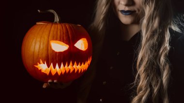 Karanlık zemin üzerinde balkabağı olan esrarengiz siyah cadı. Cadılar Bayramı 'nın korkunç sembolü, maskeli balo kostümü, parti dekorasyonu. Sihir, klasik cadı. Yüksek kalite fotoğraf