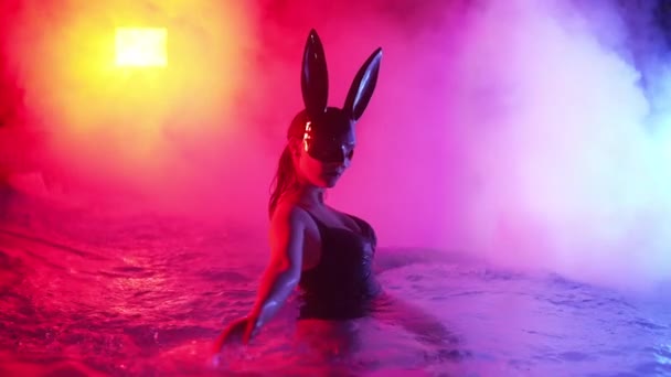 晚上穿着兔子乳胶面具的性感女人在游泳池里游泳 迷人的穿着黑色泳衣的妞享受派对时光 丰富的生活方式奢华的生活娱乐化装舞会危险的女孩 4K镜头 — 图库视频影像
