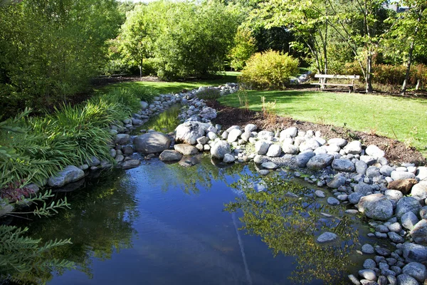 Jardín con estanque y banco — Foto de Stock
