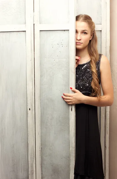 Girl peeks out from behind the closet door — Stock Photo, Image