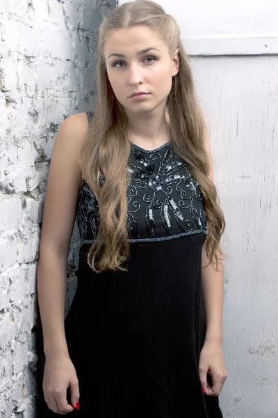 Vestido menina fica contra a parede de tijolo — Fotografia de Stock