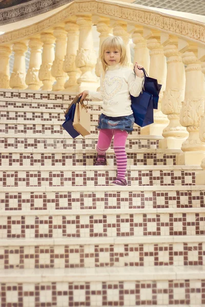 Girl 3 years old comes down stairs with shopping — Stock Photo, Image