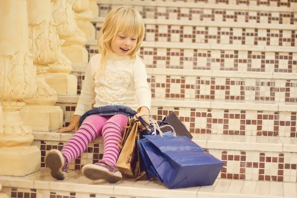 Sonriente chica rubia 3 años de edad con compras —  Fotos de Stock