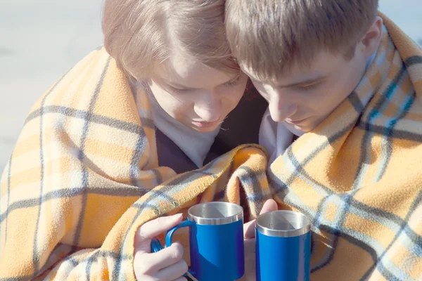 Молодая пара, обнимающаяся зимой, пьет чай — стоковое фото