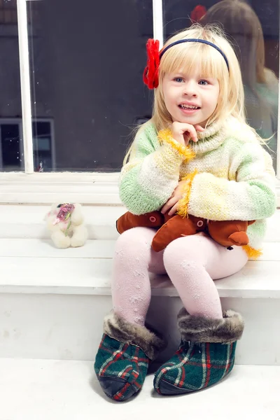 Blonde little girl in knitted sweater sitting — Stock Photo, Image