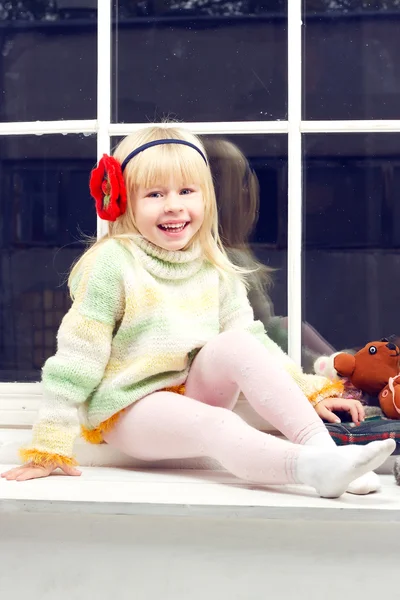 Bambina in un maglione a maglia e guarda la fotocamera — Foto Stock