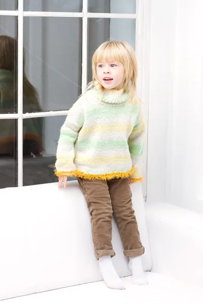 Little girl 3 years old sitting on a white couch — Stock Photo, Image