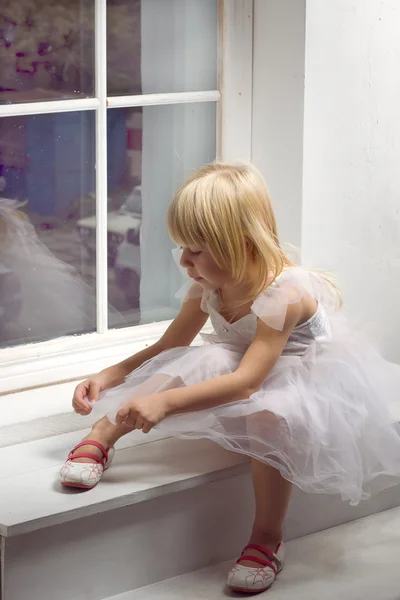 Meisje 3 jaar oud in een witte jurk in de buurt van venster — Stockfoto