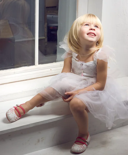 Menina 3 anos de idade em um vestido branco perto da janela — Fotografia de Stock
